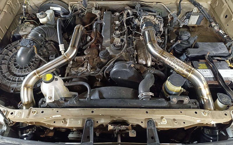 Custom symmetrical stainless boost pipes installed in an engine bay